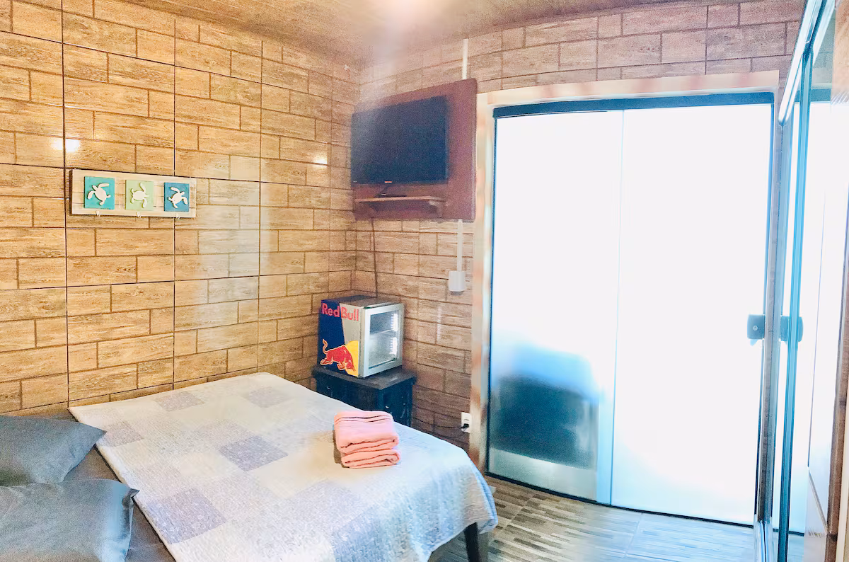 Quarto do bangalô Vento Sul, com cama de casal e vista pra varanda