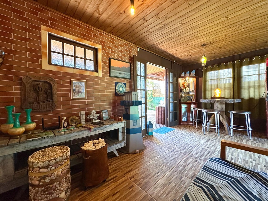 Salão comum da Aerolito, com bar, farol decorativo e parede de tijolinho